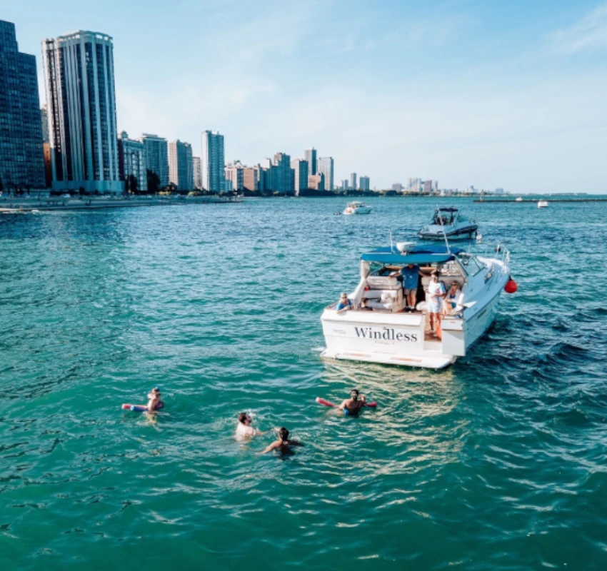 Private boat rental at the Playpen in Chicago with guests swimming near the yacht.
